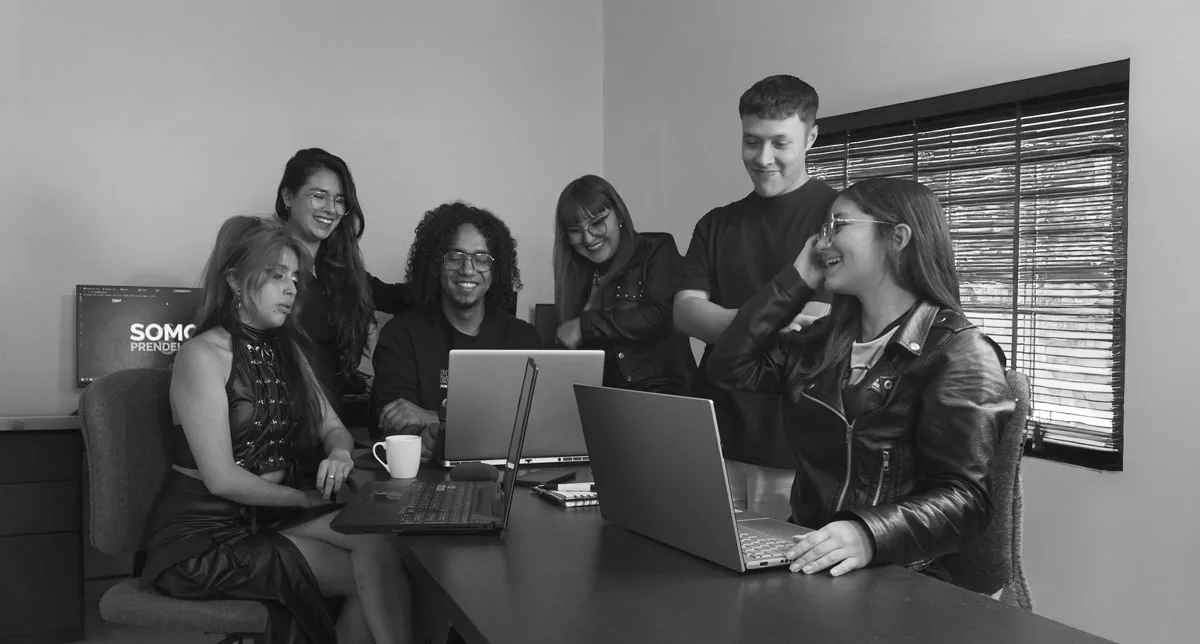 Equipo creativo de Prendelfoco colaborando en la Home con laptops en una oficina moderna a blanco y negro.